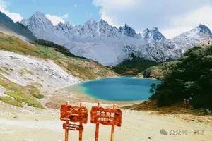 Turquoise alpine lake cradled by snowy peaks in Shangri-La, with wooden trail signs at the viewpoint on the trek