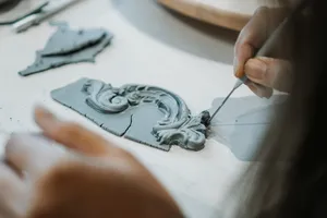 Hands carving an antique-style ceramic plate ornament with a needle tool at Ina Atelier pottery workshops in Singapore