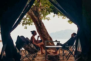 Relaxing under a shaded beach shelter with loungers and a table, overlooking trees and sea at Surin Island, Khao Lak