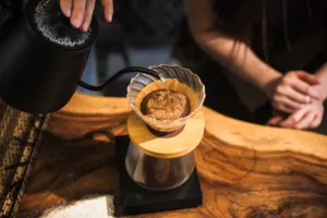 Pour-over coffee dripping into a glass dripper on a wooden table during hands-on coffee roasting workshops in Singapore