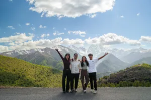 Travellers with a Tibetan guide posing on a mountain road with snowy peaks above Shangri-La during a 6-day loop trek