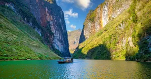 Boat floating on a calm lake between towering karst cliffs in Ha Giang during Mama’s scenic Ha Giang loop
