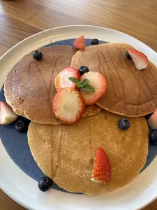 Pancake keemasan terinspirasi TCM dengan stroberi, blueberry, dan mint di atas piring biru, bagian dari lokakarya Food as Medicine di Singapura