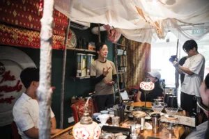 Guests listen as a host demonstrates coffee brewing with servers and equipment on a counter during brunch, workshops in Singapore