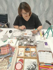 A participant adds details to her vision board for gemstones in Singapore, surrounded by collage templates, pens and jars; workshops in Singapore