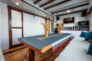 Dining table and sofa seating inside a sleek phinisi cabin on La Famille’s private 3D2N Komodo cruise in Labuan Bajo