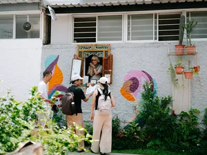 People on a Joo Chiat photo walk gather by a colourful courtyard mural, talking and holding cameras in Singapore