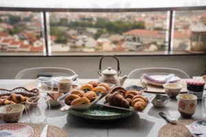 Tray of freshly baked croissants and tea cups on a dining table by a window overlooking Singapore city views