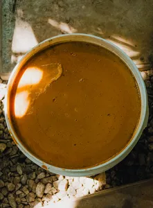 古晋 Tanoti Crafts 的砂拉越手作场景中,金属锅里的棕榈糖浆呈棕褐色,放在石头上加热